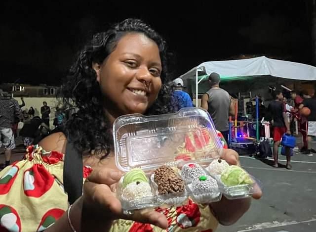 mulher negra segurando uma bandeja com doces